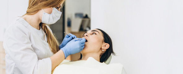 Female dentist with female patient in dental chair providing oral cavity treatment