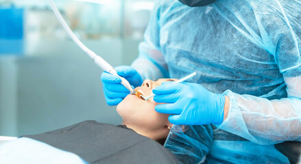 Male dentist with female patient in dental chair providing oral cavity treatment.