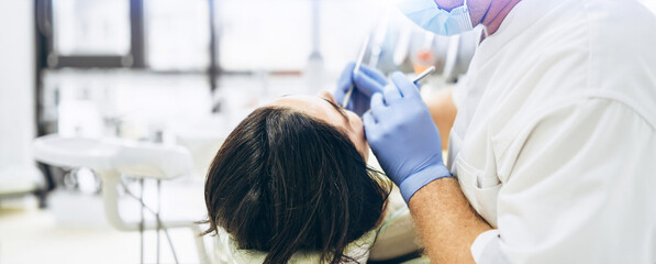 Dentist with patient in dental chair providing manipulations in oral cavity.