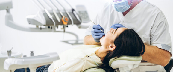Dentist with patient in dental chair providing manipulations in oral cavity.