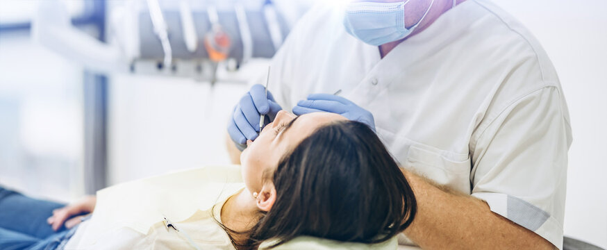 Dentist with patient in dental chair providing manipulations in oral cavity.