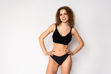 Cheerful attractive young fitness woman in black top and black lingerie over white background