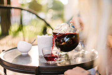 In a street cafe, in the morning, a waiter pours strong tea from a transparent glass teapot into a...