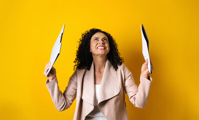 hispanic adult business woman portrait holding folders on yellow background in Mexico Latin America