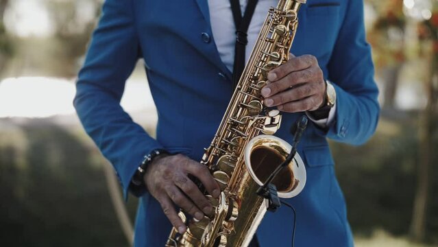 Saxophonist in blue suit playing at sunset