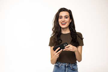 Young woman smiling while using cellphone isolated over white background