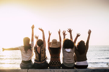Group of happy and excited females friends enjoy beach day and friendship all together sitting...