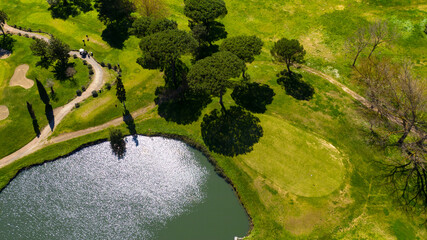 Aerial view of a golf course with many lakes and ponds. There are golfers playing a hole in the...