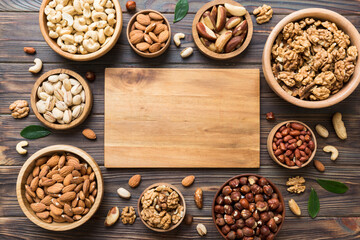 Fototapeta premium mixed nuts in wooden bowl. Mix of various nuts on colored background. pistachios, cashews, walnuts, hazelnuts, peanuts and brazil nuts