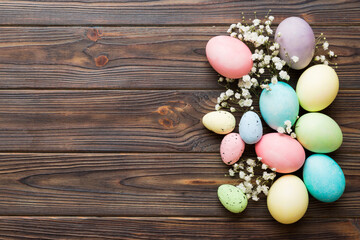 Fototapeta na wymiar Happy Easter composition. Easter eggs on colored table with gypsophila. Natural dyed colorful eggs background top view with copy space