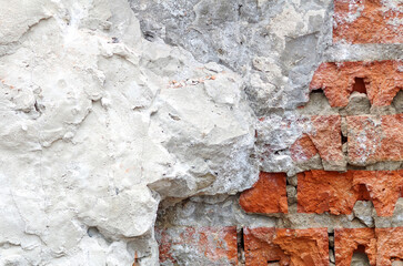 Old brick destroyed wall. Shabby facade of a building with damaged plaster.