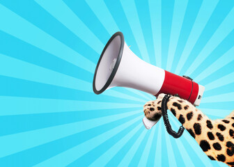 Leopard holds a loudspeaker in paw on a vintage light blue background. Business and management,...
