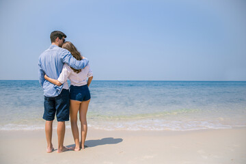 Portrait of beautiful caucasian woman with man wearing sunglasses walking on beach. Young couple enjoy honeymoon after marriage at sea. Happy casual lover hold at the tropical beach with copy space.