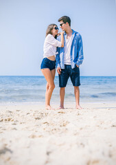 Portrait of beautiful caucasian woman with man wearing sunglasses walking on beach. Young couple enjoy honeymoon after marriage at sea. Happy casual lover hold at the tropical beach with copy space.