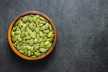 Top view of pumpkin kernels in bowl on black background