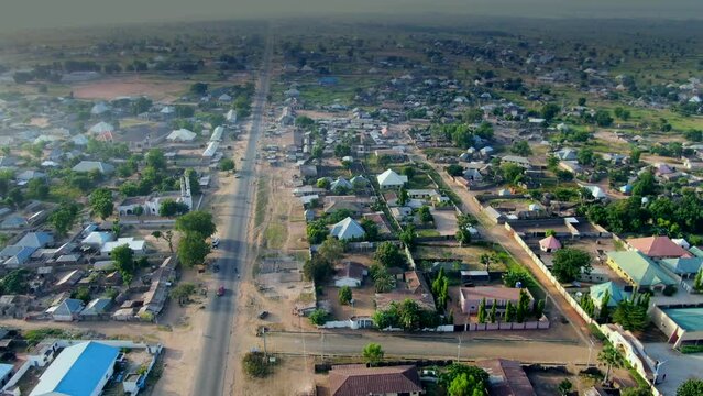 The main road through Damsa Community, Nigeria - aerial pull back reveal