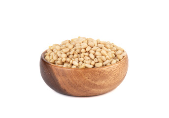 Wooden bowl full of shelled pine nuts on a white background.
