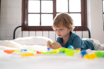 Little boy in his bedroom with a new toy purchased by his parents to help him improve his thinking skills.