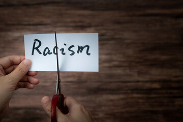 Scissors cutting word racism on paper