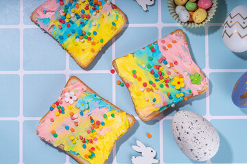Fototapeta na wymiar Cute sweet and funny Easter breakfast for kids. Homemade rainbow colored sandwiches, sandwiches with colored cream cheese and sugar sprinkles