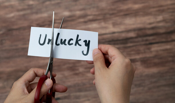 Scissors cutting word unlucky on paper
