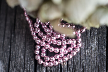 The photo shows hematite beads. This is a natural stone painted in different colors, round and hexagonal. Placed on a wooden board on a background of dried hydrangeas.