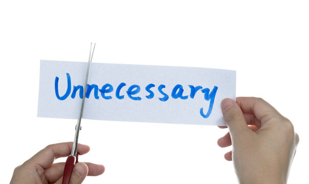 Scissors cutting word unnecessary on paper