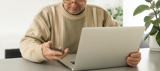 Senior man with eyeglasses connected with laptop at home.