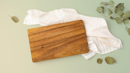 Wooden cutting board on napkin with leaves on green background