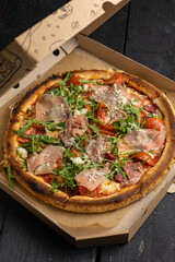 Delicious pizza with prosciutto, herbs and cheese. Food delivery
