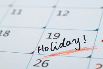 Word holiday written on calendar