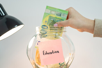 Putting euro money into glass jar with Education inscription. Saving up for education in Europe concept