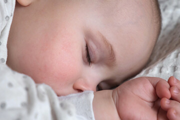 Peaceful adorable baby sleeping on his bed at home. Sleeping newborn baby concept. One year old baby girl sleeps peaceful at domestic room interior background. A serene dream. Face Close Up