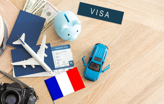 Flag of France with passport and toy airplane on wooden background. Flight travel concept