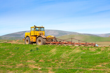 Traktok plows the land, preparing for sowing seeds. Industrial agriculture and farming. Tractor driver at work in the field. Harvesting, harvester harvests.