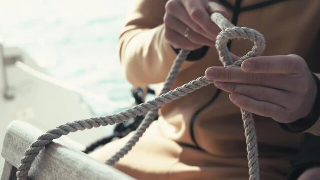 A sailor on a catamaran shows how to tie a sea knot. Close-up of hands and knot. Catamaran trip. Seaman. Sailing on a catamaran. 