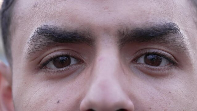 One young Middle Eastern Arab man close up eyes looking at camera in macro expression. 20s male person closeup eye
