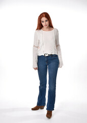 full length portrait of beautiful woman model with long red hair, wearing casual outfit white blouse  top and denim jeans, isolated on white studio background. standing pose, walking towards the camer