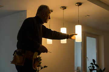 Elderly man changing light bulbs : Retired man doing household chores, replacing the light bulbs...