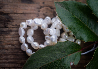 Natural freshwater pearls of various shapes and colors are photographed on a wooden board and a...