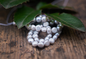 Natural freshwater pearls of various shapes and colors are photographed on a wooden board and a piece of leather.