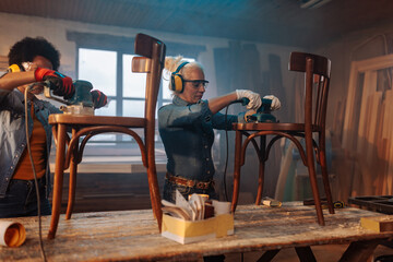 Female carpenters sanding furniture in workshop.