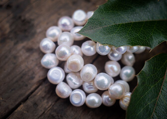 Natural freshwater pearls of various shapes and colors are photographed on a wooden board and a...