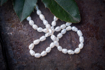 Natural freshwater pearls of various shapes and colors are photographed on a wooden board and a...