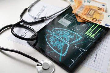Modern social health insurance program. Tablet computer with healthcare application interface on screen. Stethoscope, x-ray image and cardiogram on wooden desk. Digital healthcare technologies