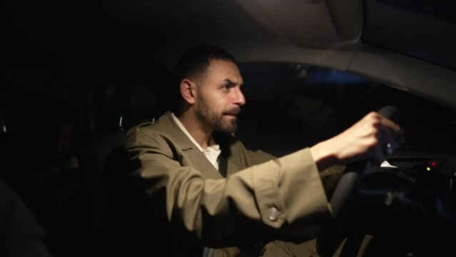 Stressed man driving on road at night having rage road. One frustrated male person holding car steering wheel on highway being late and complaining