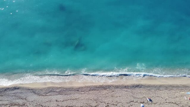 Aerial view of beautiful sandy beach with footprints and soft turquoise ocean wave. Tropical sea in summer season on Kathisma beach on Lefkada island.
