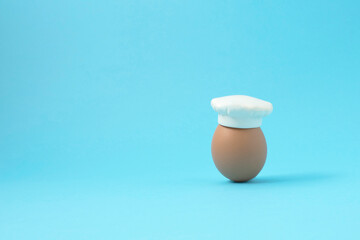 Chef hat with raw egg concept on pastel blue background. Minimal idea food. Creative concept.  