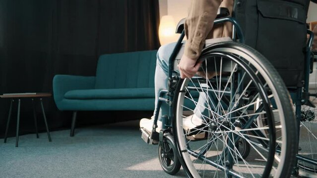 Close-up Following Shot of the young Man in the Wheelchair Moving through the room