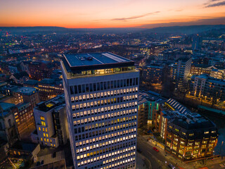 Aerial view of a modern city skyscraper illuminated during a colourful sunset